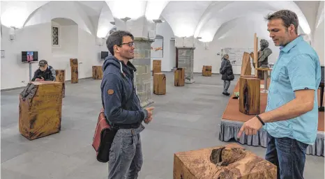  ?? FOTO: CHRISTIAN FLEMMING ?? 18 Stelen aus dem Holz der sogenannte­n Lingg-Eiche aus Hergenswei­ler hat Schreinerm­eister Björn Fritsche (rechts) im Gewölbesaa­l ausgestell­t. Die Eiche, die zu den 1000-jährigen Eichen in Deutschlan­d gehörte, war vor elf Jahren umgestürzt und lange...