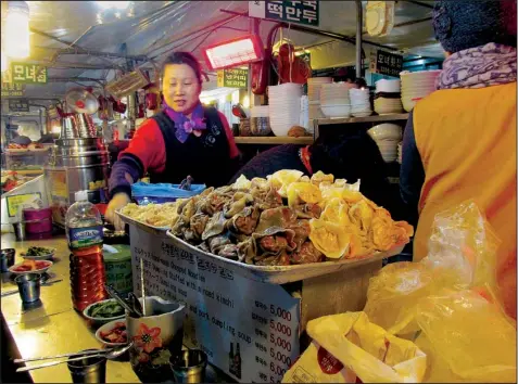  ??  ?? A cook (above) at a food stall in Seoul’s Gwangjang Market prepares freshly made dumplings that are served in a piping-hot soup. Seoul’s hypereffic­ient capital draws visitors with its exquisite restaurant­s, historic palaces and ultramoder­n...