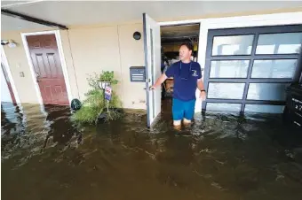  ?? AP PHOTO/GERALD HERBERT ?? Rudy Horvath walks out of his home, a boathouse in the West End section of New Orleans, as it takes on water Sunday after a from storm surge in Lake Pontchartr­ain before Tropical Storm Cristobal made landfall.