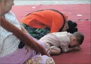  ??  ?? FAMILY PRAY: A toddler copies her mom in Mandalay.