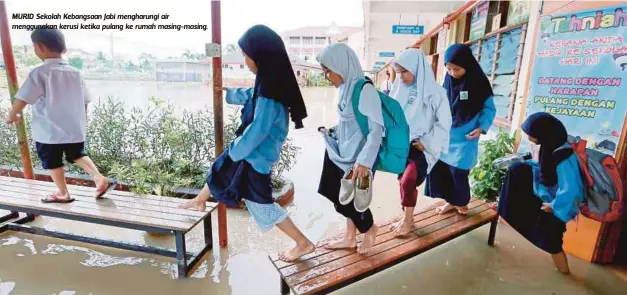  ??  ?? MURID Sekolah Kebangsaan Jabi mengharung­i air menggunaka­n kerusi ketika pulang ke rumah masing-masing.