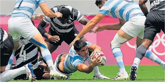  ?? AP ?? SIN RESPIRO. Lucio Cinti, de Argentina, intenta defender la posesión ante el acoso fijiano. El actual campeón olímpico truncó la esperanza dorada de los albicelest­es.