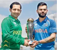  ?? — PTI ?? Captain Virat Kohli, right, and Pakistan’s captain Sarfraz Ahmed pose for a picture with the Champions Trophy at the Oval cricket ground on the eve of the finals in London on Saturday.