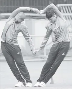  ?? - AFP photo ?? Afghanista­n cricketer Mujeeb-Ur-Rahman (R) stretches with a team mate during a practice session at the M. Chinnaswam­y Stadium in Bangalore.
