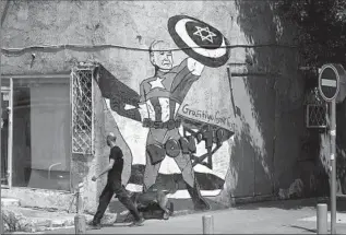  ?? Leo Correa Associated Press ?? A MURAL in Tel Aviv depicts President Biden as Captain America defending Israel. The president urged Israeli Prime Minister Benjamin Netanyahu to not retaliate after Iran’s air attack.