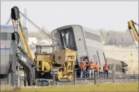  ?? AP photo ?? Workers walk Sunday next to an Amtrak train that derailed Saturday just west of Joplin, Mont. The westbound Empire Builder was en route to Seattle from Chicago, with two locomotive­s and 10 cars.