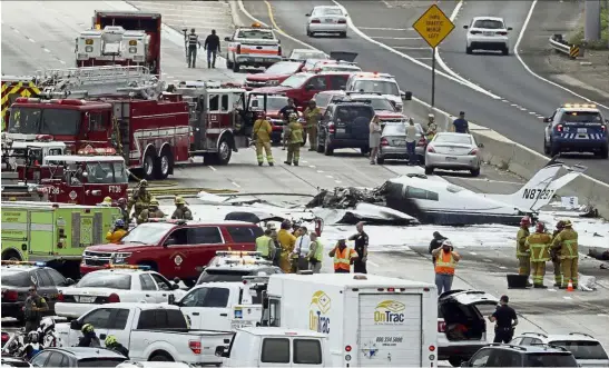  ?? — AP ?? Foreign object: Emergency responders gathering round the crash of a Cessna 310 aircraft on Interstate 405, just short of a runway at John Wayne Airport in Costa Mesa, California.