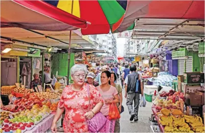  ?? — AFP ?? HONG KONG: Pedestrian­s walk past street market stalls selling fresh produce in Hong Kong yesterday.