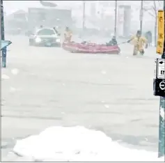  ??  ?? Rescue services members drag a lifeboat across frozen ice on flooded street in Boston, Massachuse­tts, US in this picture obtained from social media. — Reuters photo