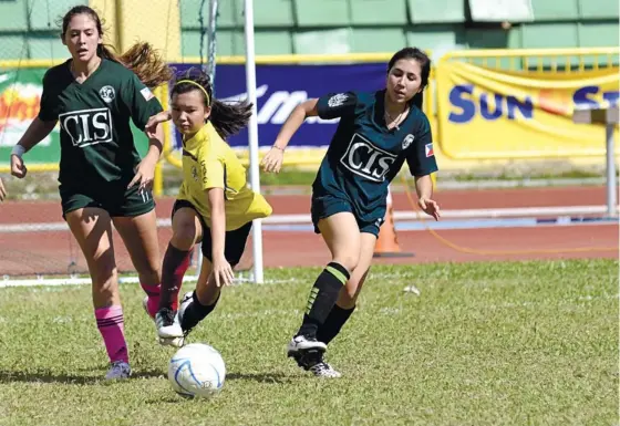  ?? (SUN.STAR FOTO/AMPER CAMPAÑA) ?? TWO VS. ONE. A player from Sacred Heart School-Hijas tries to beat two CIS defenders for the ball in their eliminatio­n round encounter.