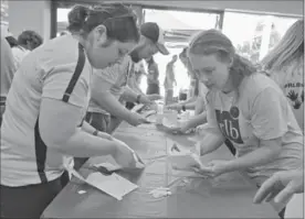  ?? IAN STEWART, SPECIAL TO THE RECORD ?? Natasha Yates, left, and Rebecca Hahn of Team RBL work on the final challenge of the Race Around the Region Challenge at police headquarte­rs during United Way kickoff.