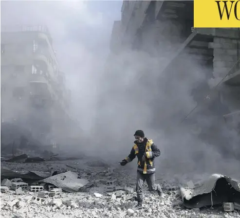  ?? ABDULMONAM EASSA / AFP / GETTY IMAGES ?? A civil defence volunteer checks the site of an airstrike in the rebel-held town of Saqba, in the Eastern Ghouta region outside of Damascus, on Friday. Another 32 civilians were killed in the sixth straight day of Syrian regime air strikes.