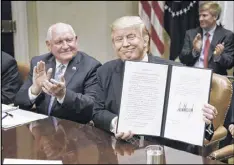  ?? OLIVIER DOULIERY / TNS ?? President Donald Trump signs the executive order Promoting Agricultur­e and Rural Prosperity in America as agricultur­e secretary Sonny Perdue looks on during a roundtable with farmers April 25.