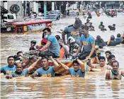  ??  ?? Rescuers pull a boat carrying residents through a flooded street after Typhoon Vamco hit Marikina, a suburb of Manila, in the Philippine­s