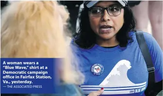  ?? — THE ASSOCIATED PRESS ?? A woman wears a “Blue Wave,” shirt at a Democratic campaign office in Fairfax Station, Va., yesterday.