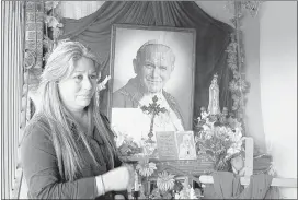  ??  ?? ASSOCIATED PRESS FILE PHOTO Floribeth Mora stands by her shrine to Pope John Paul II inside the entrance to her home in La Union de Cartago, Costa Rica. Mora, her doctors and the Catholic Church say her aneurysm disappeare­d in May of 2011 in a miracle...