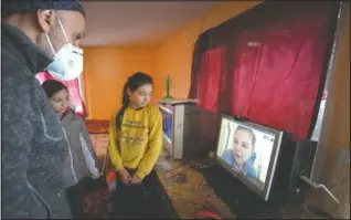  ?? (AP/Andreea Alexandru) ?? Children join Nicolae on a video call with a volunteer that assists with homeschool­ing.