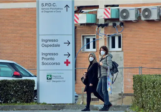  ??  ?? Due donne escono dall’ospedale di Alzano indossando la mascherina. I primi casi di contagio nella Bergamasca si sono verificati nella struttura