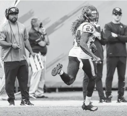  ?? Photos by Brett Coomer / Staff photograph­er ?? The Texans’ Tremon Smith looks back over his shoulder en route to completing a 98-yard kick return for a touchdown on Sunday.