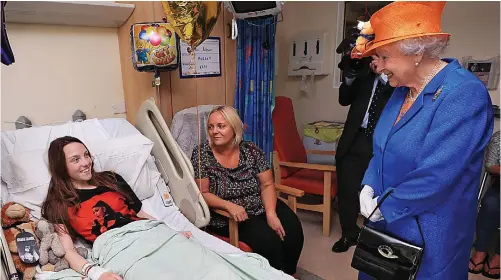  ??  ?? Cheering smile: Her Majesty lifted the spirits of Millie Robson, 15, who suffered severe leg injuries in the blast