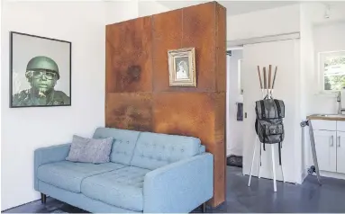  ??  ?? A feature wall in the open space hides the bathroom and service area; a sliding barn door conceals built-in storage.