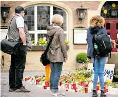  ?? DPA-BILD: KIRCHNER ?? Passanten stehen am Tatort. In Gedenken an die Opfer wurden hier Kerzen und Blumen niedergele­gt.