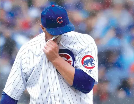  ?? AP ?? Jon Lester wipes the rain from his face after allowing Matt Carpenter’s second homer. His ERA rose from 2.58 to 3.14 after he allowed eight runs in three-plus innings.