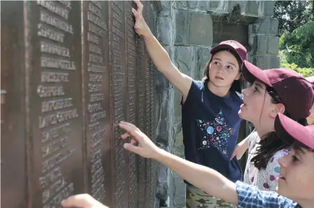  ??  ?? Zoe Spenceley, left, Alice Goldberger and Sasha Cellino visit the Wall of Remembranc­e, part of the memorial to the Fallen Soldiers of the Royal Newfoundla­nd Regiment in Bowring Park in St. John’s, N.L., on Thursday. The young British students from...