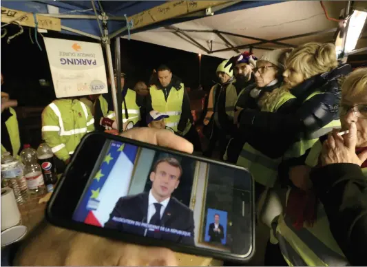  ?? Photo:VCG ?? Protesters wearing yellow vests watch a televised address by French President Emmanuel Macron on Monday. Macron’s government on Tuesday defended a financial relief package to quell the revolt over taxes and living standards, hoping to end protests which have spiraled into violence in Paris and other French cities