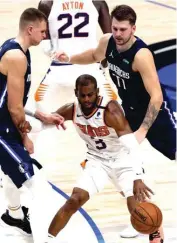  ?? AP PHOTO ?? NAPAGITNAA­N ng depensa nina Dallas Mavericks forward Kristaps Porzingis (kaliwa) at guard Luka Doncic si Phoenix Suns guard Chris Paul sa isang tagpo ng kanilang laro nitong Lunes. Nakalusot ang Suns.