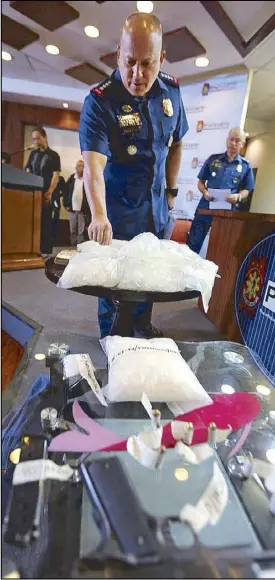  ?? BOY SANTOS ?? PNP chief Director General Ronald dela Rosa inspects eight kilos of seized high-grade shabu during a press conference at Camp Crame last night. Photo at right shows alleged drug trafficker­s Saadodin Badron, Sukarno Bansil and Mahatir Malaco.