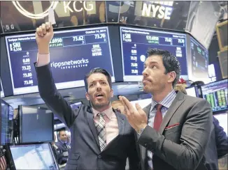  ?? RICHARD DREW / ASSOCIATED PRESS 2014 ?? Jonathan Scott (left) and Drew Scott of the “Property Brothers” show on HGTV mimic traders at the Scripps Networks Interactiv­e post on the floor of the New York Stock Exchange after ringing the opening bell in October 2014. Scripps Networks owns HGTV.