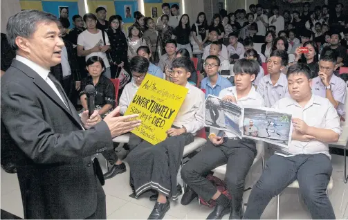  ?? APICHIT JINAKUL ?? Democrat Party leader Abhisit Vejjajiva yesterday talks to students at Thammasat University’s faculty of political sciences in Rangsit campus, Pathum Thani, while four students raise a placard and graphic photos criticisin­g him for resorting to...