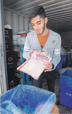  ?? CATHIE COWARD THE HAMILTON SPECTATOR ?? Ali Shah packs rice and oil along with other halal food staples into a food hamper box at the Mishkah Social Service Barakah Box food bank.