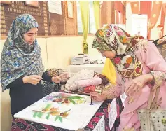  ??  ?? A visitor tries her hand at painting ‘Batik Sarawak’ during the visit.