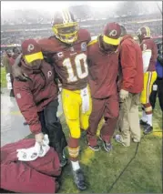  ??  ?? Washington Redskins quarterbac­k Robert Griffin III is helped off the field after a second-half injury against the Baltimore Ravens on Sunday.