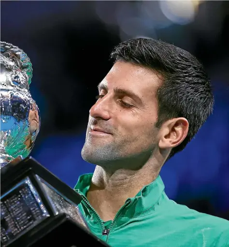  ?? GETTY IMAGES ?? New world No 1 Novak Djokovic stares lovingly at the Australian Open trophy – his 17th career grand slam.