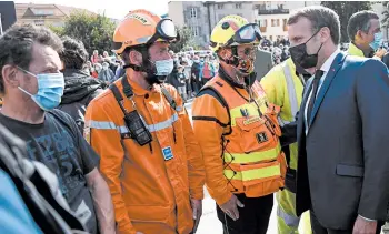  ?? CHRISTOPHE SIMON/AP ?? Macron visits flood-ravaged Alps: French President Emmanuel Macron, right, meets with rescuers Wednesday in an area in the Alps near the Mediterran­ean where storm flooding has swept away homes and unearthed bodies from cemeteries. With at least 13 dead and others missing, France and Italy are assessing damage after the violent rains.