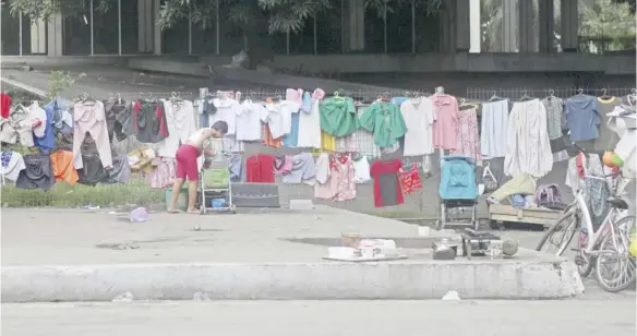  ?? PHOTOGRAPH BY JOEY SANCHEZ MENDOZA FOR THE DAILY TRIBUNE @tribunephl_joey ?? THIS laundrywom­an takes advantage of the sunlight to hang clothes to dry easily in a vacant lot along 13th and Railroad streets in Port Area, Manila Wednesday.