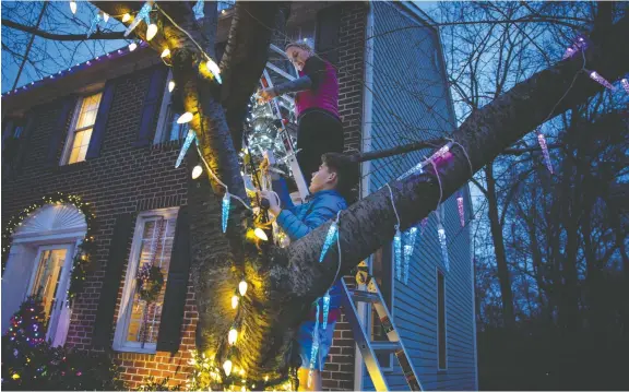  ?? EVELYN HOCKSTEIN/ THE WASHINGTON POST ?? Lighting your home at Christmas has changed a lot over the years, as Colter Zimmer, 13, and his mom, Julie Zimmer, demonstrat­e at their home. These are not your grandmothe­r's string of Christmas lights.