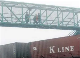  ??  ?? Port workers cross a bridge on their return to work at the Port of Long Beach on Wednesday. Work resumed at the Los Angeles and Long Beach harbors after the settlement of a strike that crippled the complex for more than a week.