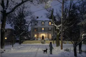  ?? (AP/David Goldman) ?? Neighbors stop and talk while out at dusk following a snowfall Sunday in Providence, R.I.