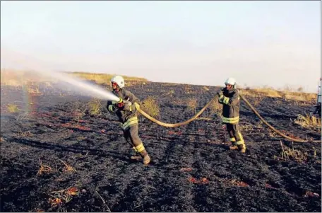  ?? Syrian Civil Defense White Helmets ?? CIVIL DEFENSE workers try to extinguish a fire in a field in Kfar Ain, in northweste­rn Syria’s Idlib province. Thousands of acres of wheat and barley fields in Syria and Iraq have been scorched by the fires during the harvest season, which runs until mid-June.