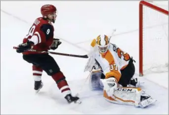  ?? ROSS D. FRANKLIN — THE ASSOCIATED PRESS ?? Arizona’s Clayton Keller (9) catches Flyers goaltender Brian Elliott (37) with his stick during the shootout Saturday in Glendale, Ariz. Elliott was forced to leave the game.