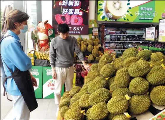  ?? ZHU LILI / XINHUA ?? A consumer (right) checks out imported durian at a fruit store in Nanning, Guangxi Zhuang autonomous region, in April last year.