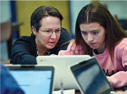  ?? AP Photo/Stephen Dunn ?? In this Dec. 20 photo, Jennifer Rocca, left, a teacher librarian at Brookfield, Conn., High School, works with Ariana Mamudi, 14, a freshman in her Digital Student class. The required class teaches media literacy skills and has the students scrutinize...