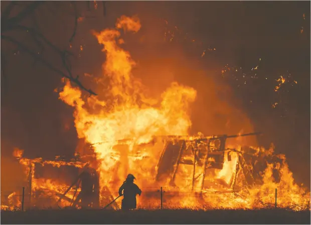  ?? Dan Himbr echts / AAP Ima ges via AP ?? New South Wales Rural Fire Service crews fight the Gospers Mountain fire as it engulfs a structure in the town of Bilpin on the weekend.