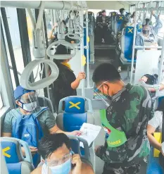  ?? ALDO NELBERT BANAYNAL ?? A police officer flags down a passenger bus on Escario Street in Cebu City yesterday to check quarantine passes and IDs.