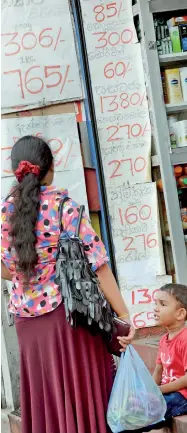  ??  ?? What changed, what's not: A woman checks out a price list put up in front of a boutique.
Pic by Indika Handuwala