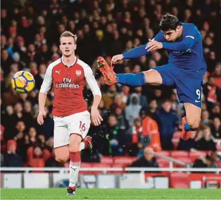  ?? AFP PIC ?? Chelsea’s Alvaro Morata (right) takes a shot at goal as Arsenal’s Rob Holding looks on in a Premier League match at the Emirates Stadium on Wednesday.